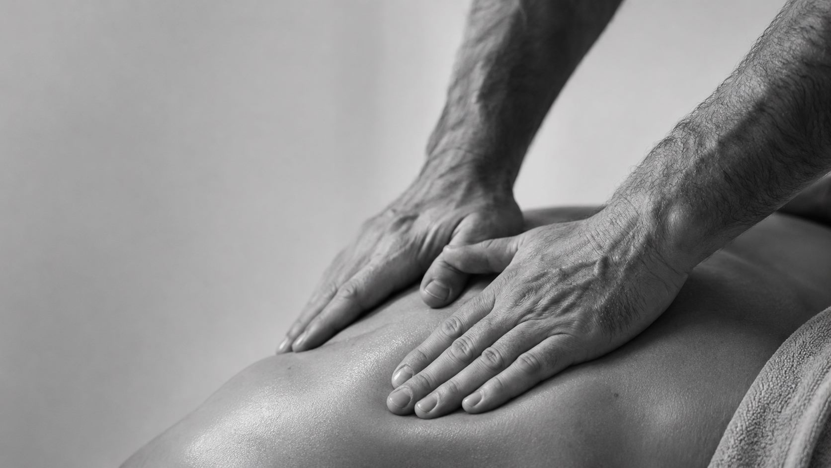 Heilmasseur behandelt mit beiden Händen den Rücken einer liegenden Person